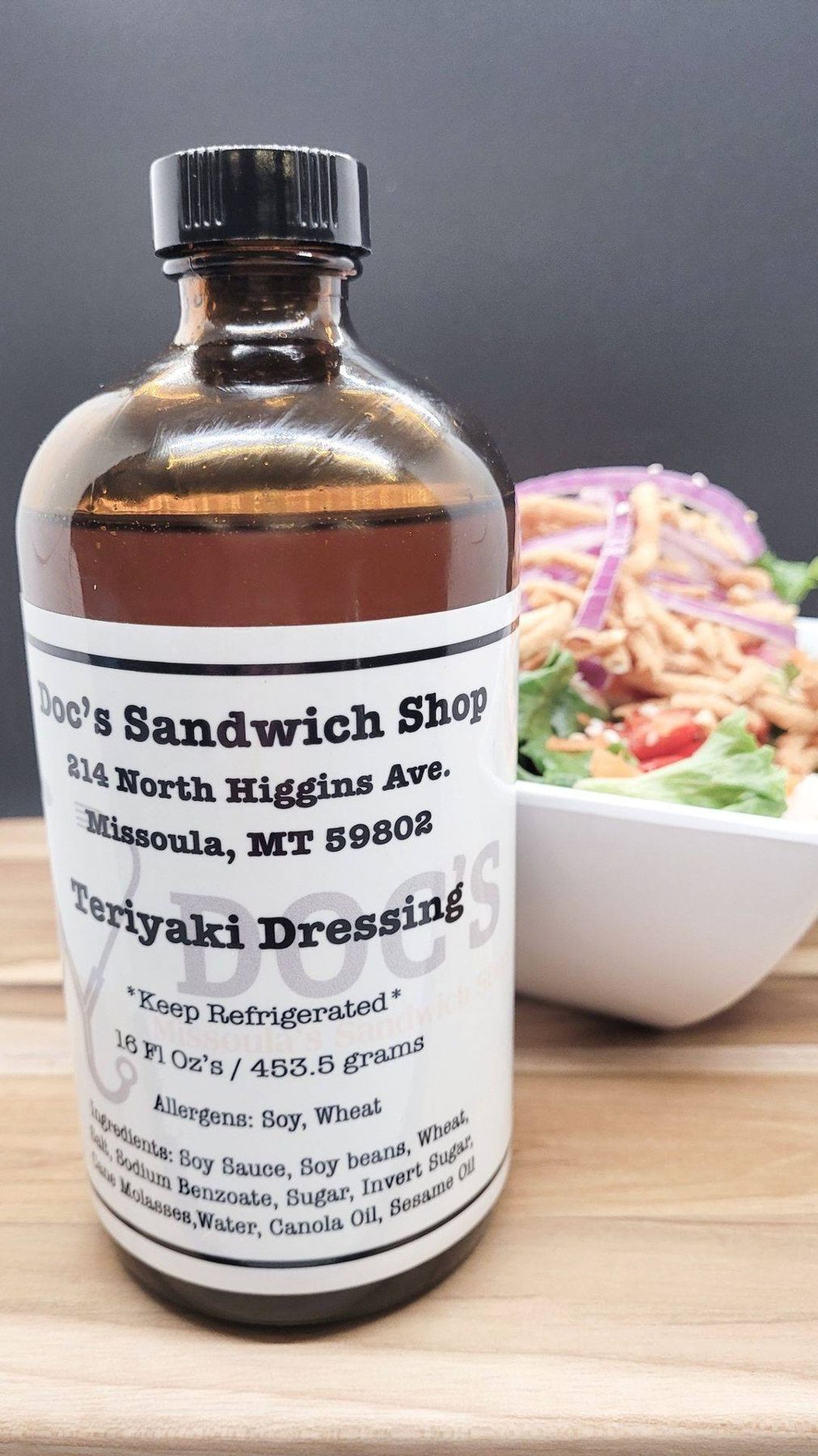 A bottle of Doc's house teriyaki dressing beside a salad