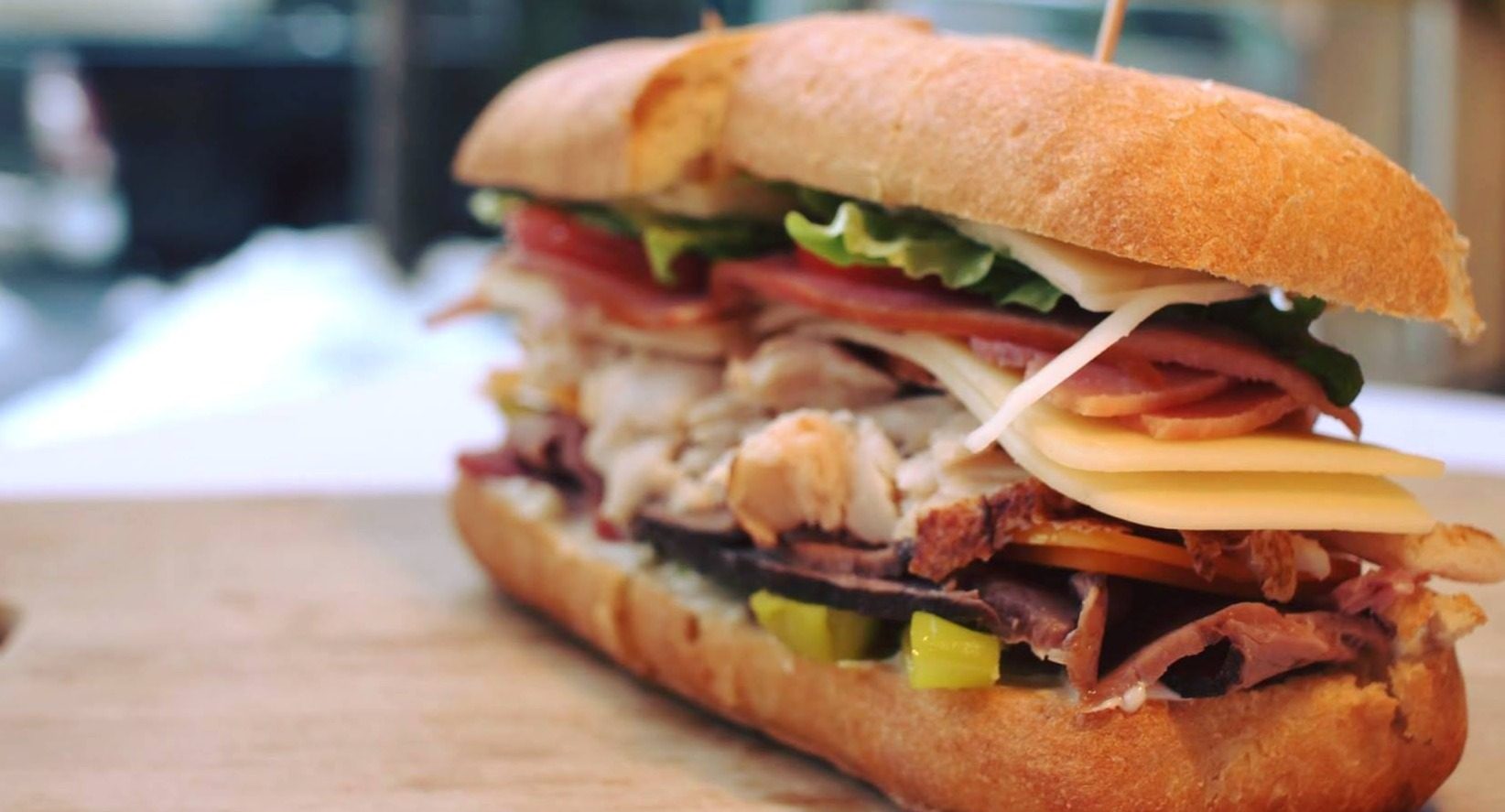 A layered Doc's sandwich on a French roll with salami, provolone, lettuce and tomato